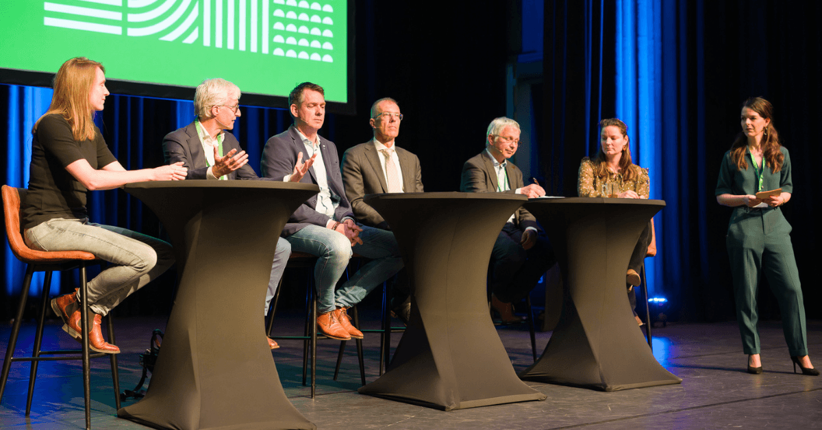 6 personen zitten op een kruk op het podium