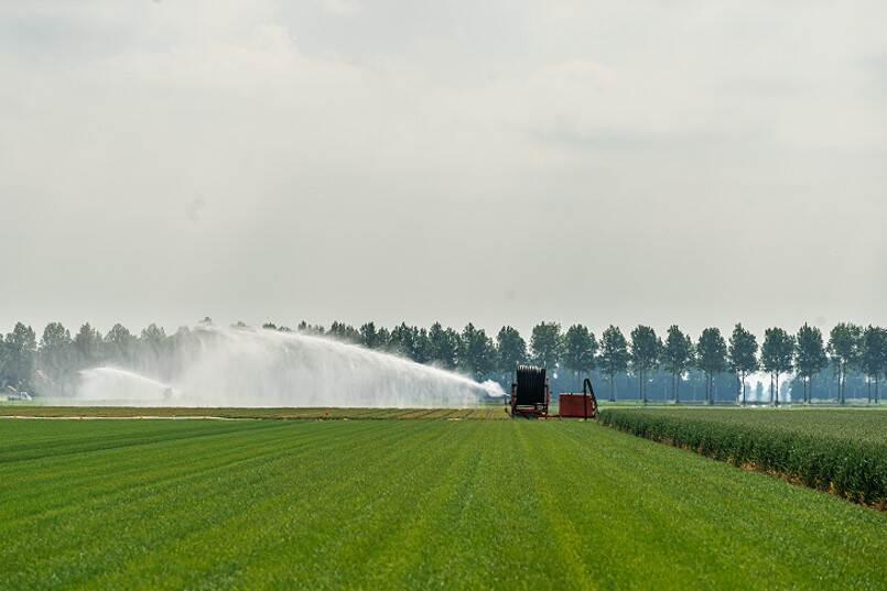 Weiland met water sproeiend landbouwvoertuig