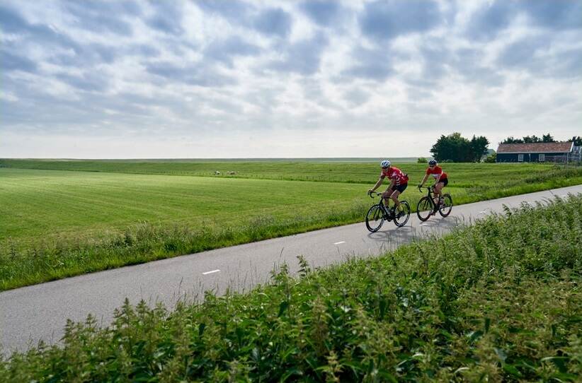 2 wielrenners met weiland op de achtergrond