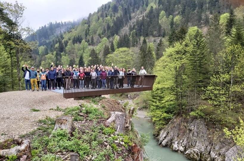 groep mensen op een brug tussen beek en bergen