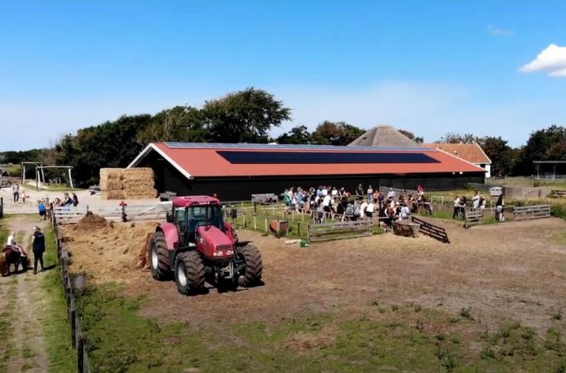 Boerderij met rode tractor en veel mensen
