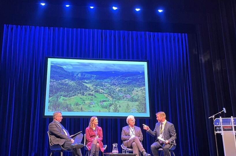 Panel aan mensen zittend op podium voor groot beeldscherm