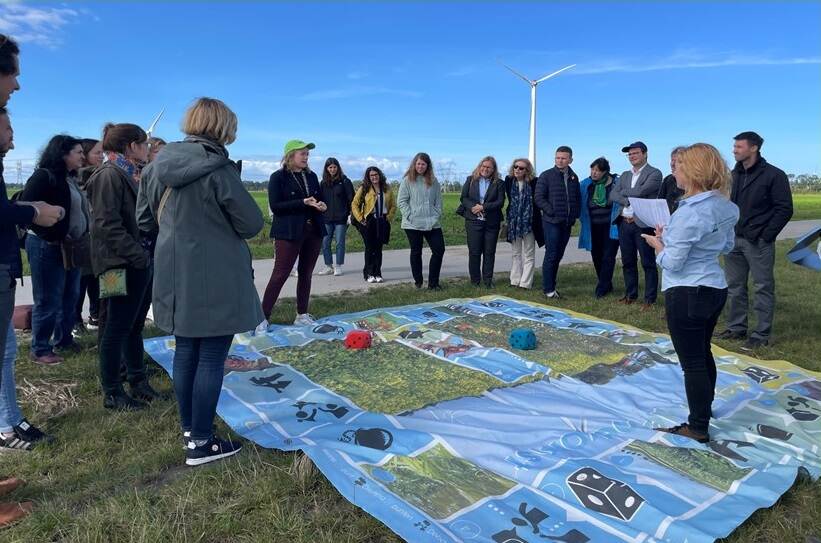 kring mensen om een groot bordspel heen in weiland