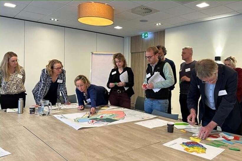 Groepje mensen leunend over tafel tijdens werksessie