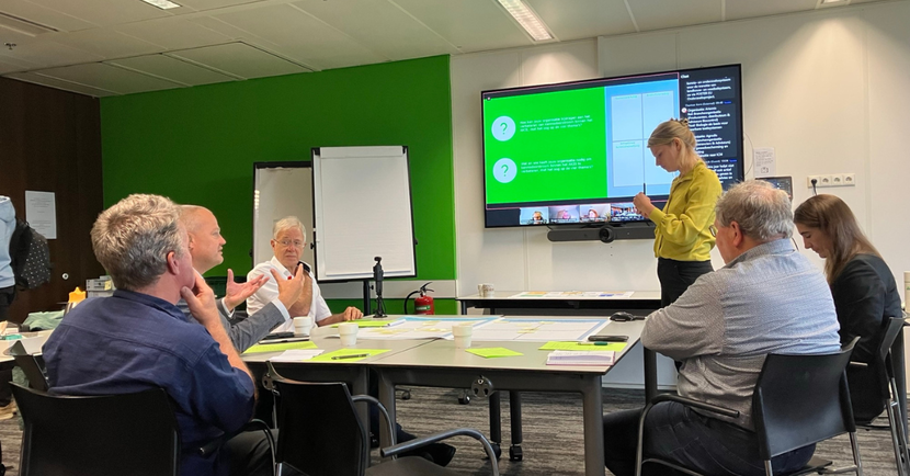 groep mensen kijkend naar scherm met presentatie